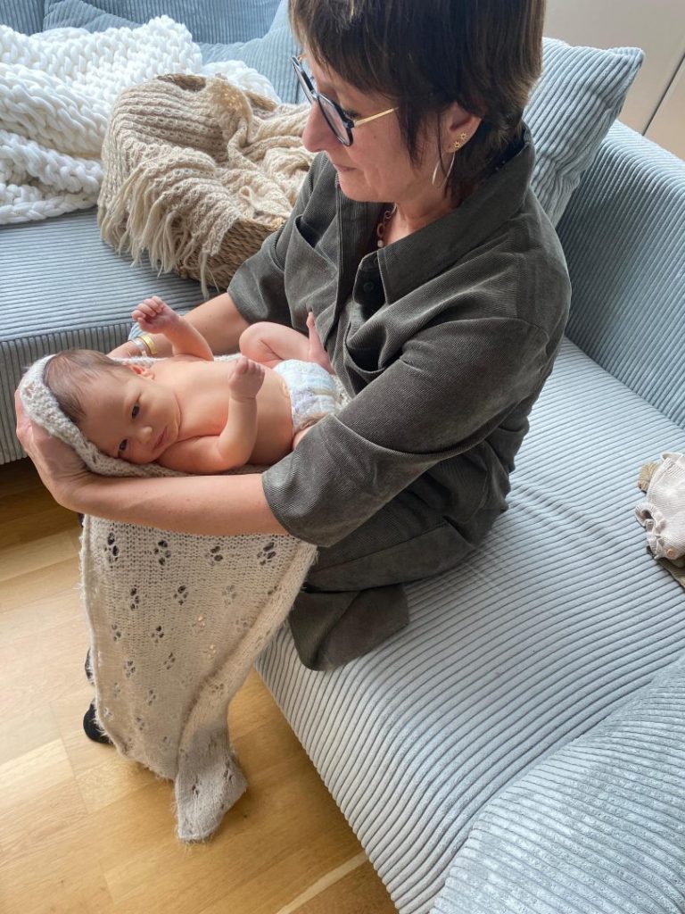 Fotograf Petra Wanzki wickelt beim Newborn Shooting das Baby sanft in ein Tuch ein.