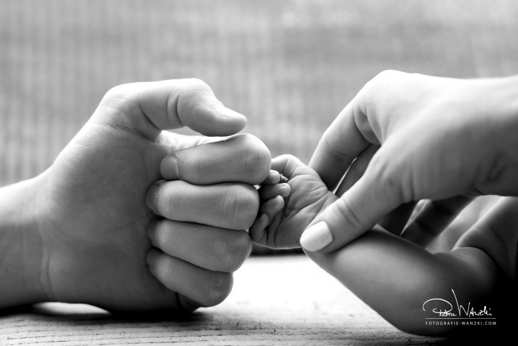 Baby Faust wird von Mamas Hand beim Fotoshootings in Winterthur gehalten und stösst zu Papas Hand, Bild in schwarz weiss