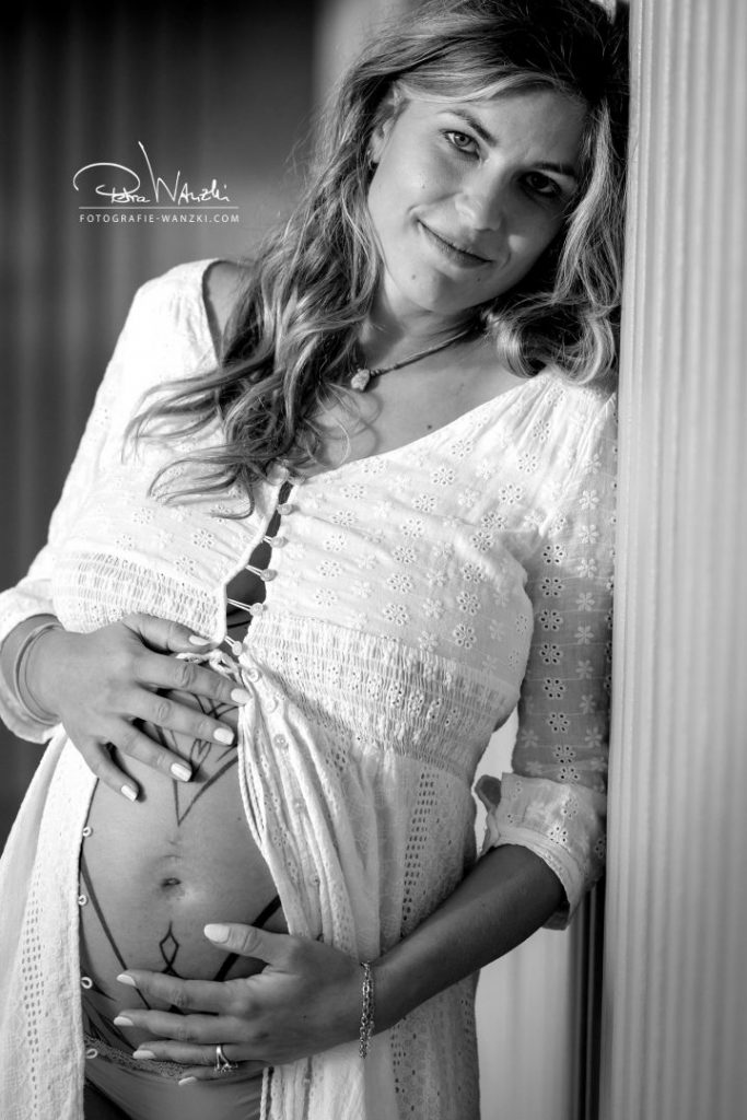 Schwangere Mama lehnt an einer Wand und streichelt sich den Babybauch, Schwarz-weiss Fotografie aus Winterthur