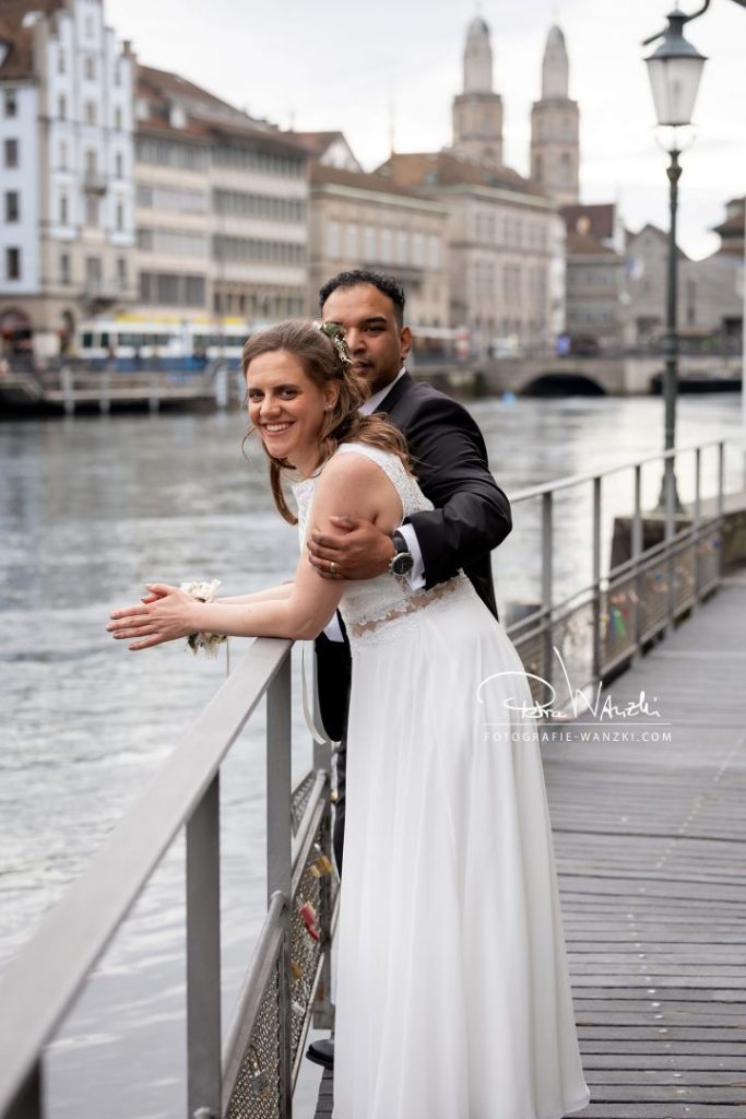 Brautpaar am Steg an der Limmat in Zürich, Braut lehnt sich über das Geländer, im Hintergrund das Grossmünster Zürich