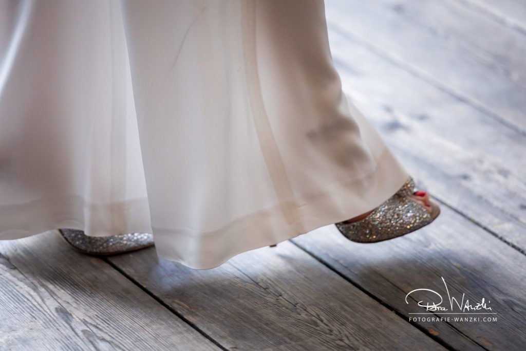 Braut in modernem Hosenanzug, Jumpsuite, glitzernde Hochzeitschuhe, rot lackierte Fussnägel, Braut geht locker über Holzboden, DetailAufnahme