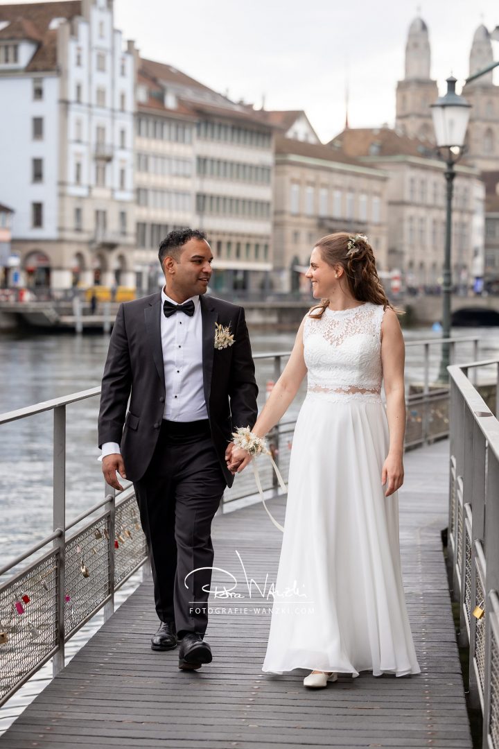 Hochzeit im Zivilstandesamt Zürich, Brautpaar Hand in Hand an der Limmat, im Hintergrund Grossmünster