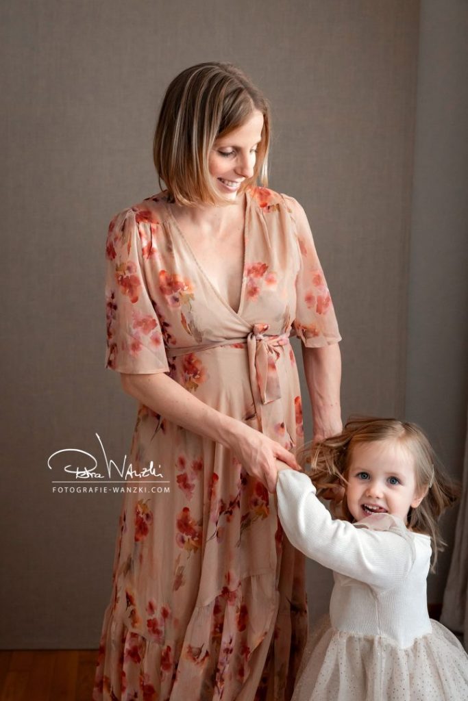 Tanzendes, glückliches Mädchen wird von der schwangeren Mutter an der Hand gehalten, im Fotostudio in Winterthur