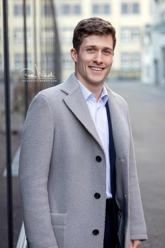Bewerbung FotoShooting Winterthur, junger Mann im Mantel lacht in die Kamera der Fotografin aus Winterthur, urbaner Look,