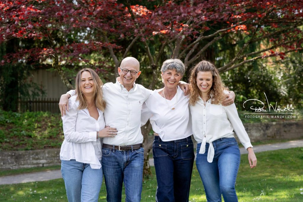 glueckliche Familie, Arm in Arm, alle lachen, haben Spass, alle haben Jeans und weisses Oberteil an