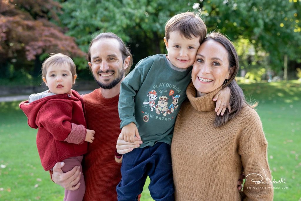 Glückliche Familie umart sich und lacht, 2 Kinder, der Junge umarmt die Mutter