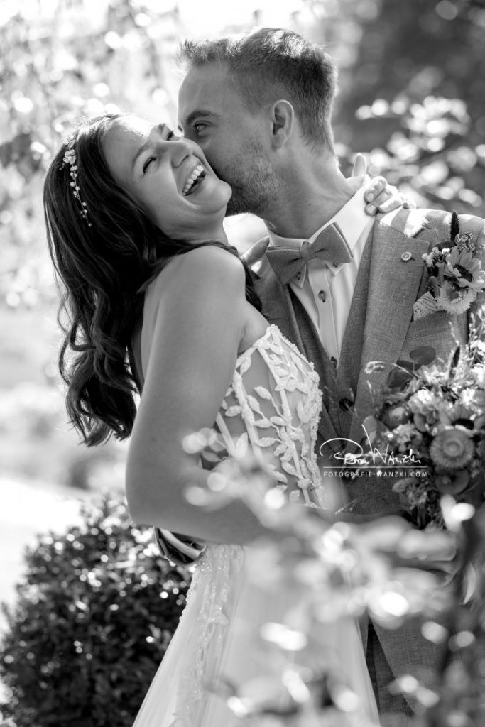 Lachendes und glückliches Brautpaar vom Hochzeitsfotograf Winterthur fotografiert, mitten im Grünen, Gegenlicht