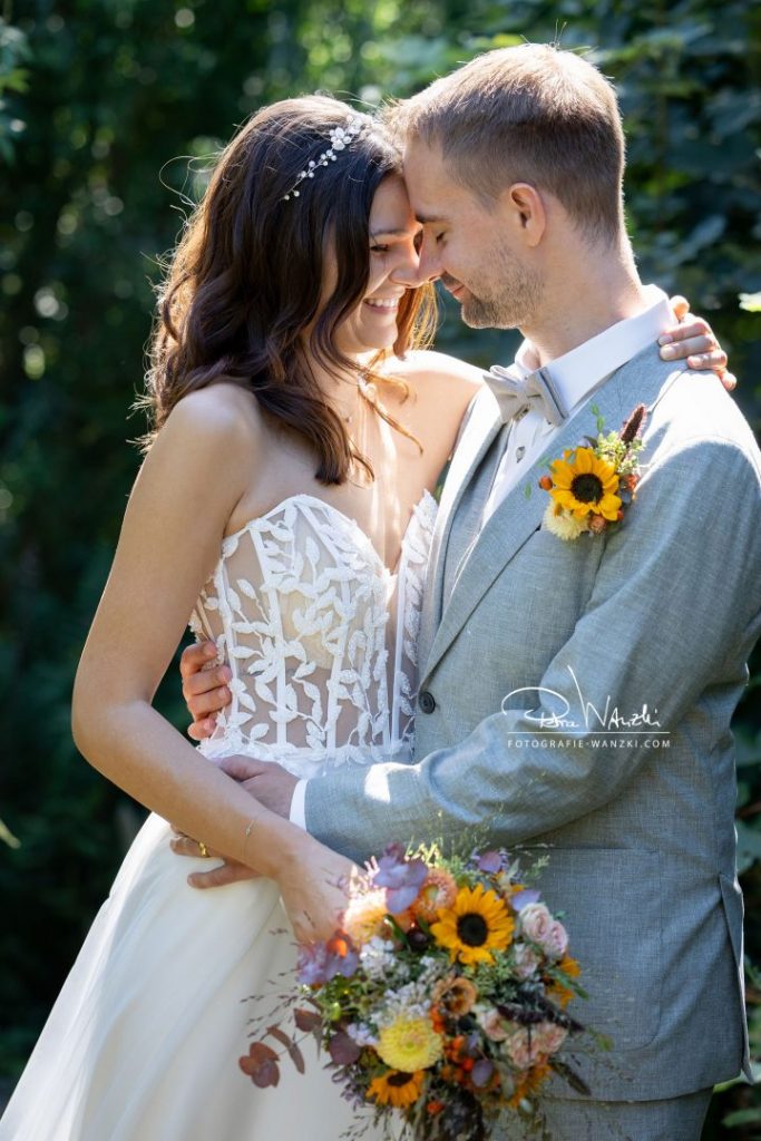 moderne Brautpaar hält sich umarmt, lächelt, die Augen sind geschlossen, Hochzeit im Garten von Am Charrewäg bei Illnau