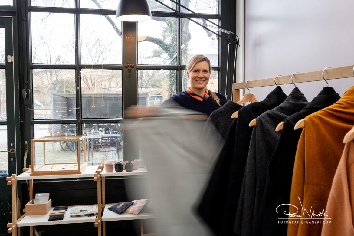 Künstlerin in ihrem Atelier im Industriestyle in Winterthur, sie holt mit Schwung ein Mantel von der Kleiderstange