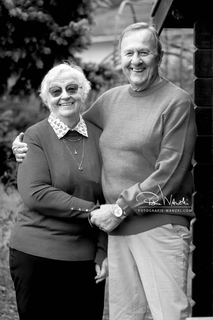 Grosseltern umarmen sich und lachen in die Kamera, Bild in Schwarz-weiss