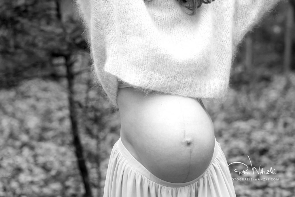 bauchfreier Kuschelpullover trägt die schwangere Frau über dem Babybauch, der Bauch wird so optimal zur Geltung gebracht, Bild in schwarz-weiss 