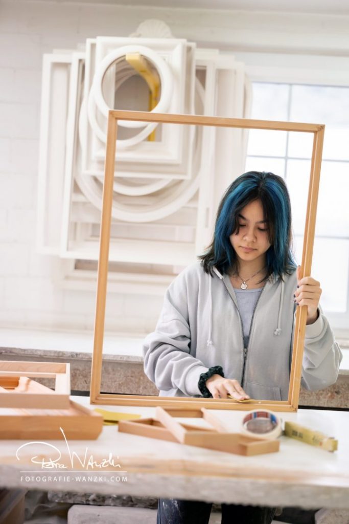 Künstlerin bei der Arbeit für das Business FotoShooting in Winterthur, sie schleift einen Bilderrahmen ab und hält den Rahmen in der Hand