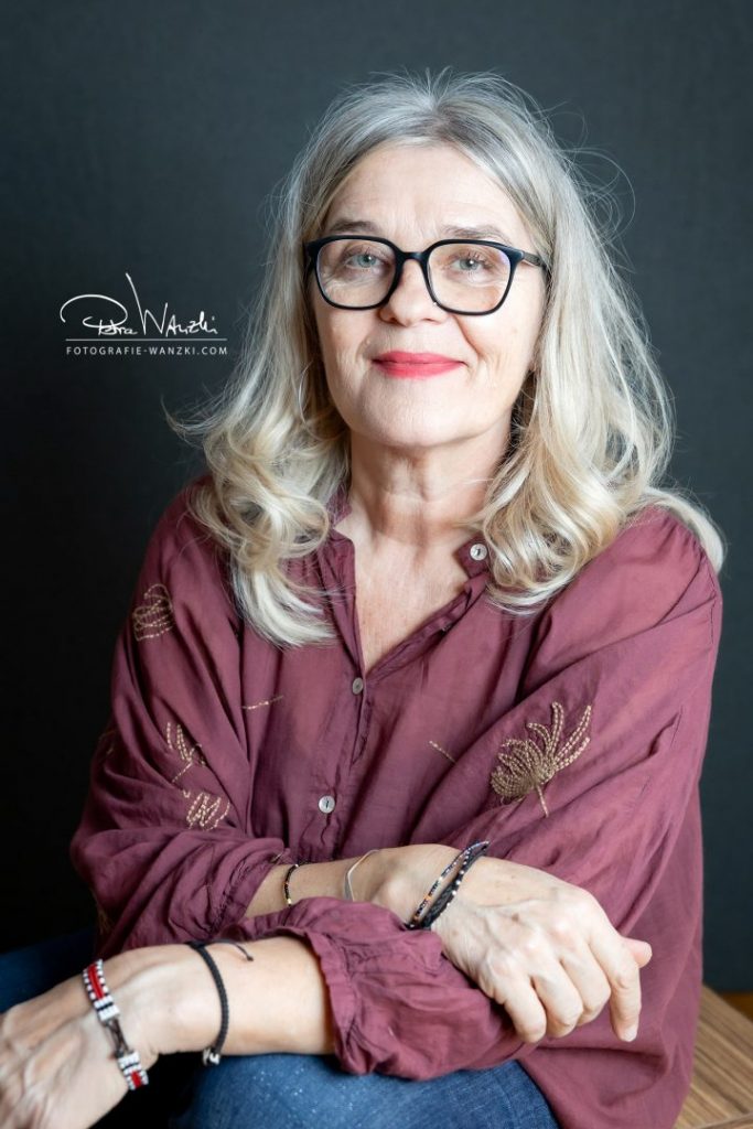 Freut mit Brille schaut selbstbewusst für das Bewerbungsfotoshooting in Winterthur in die Kamer, dunkler Hintergrund