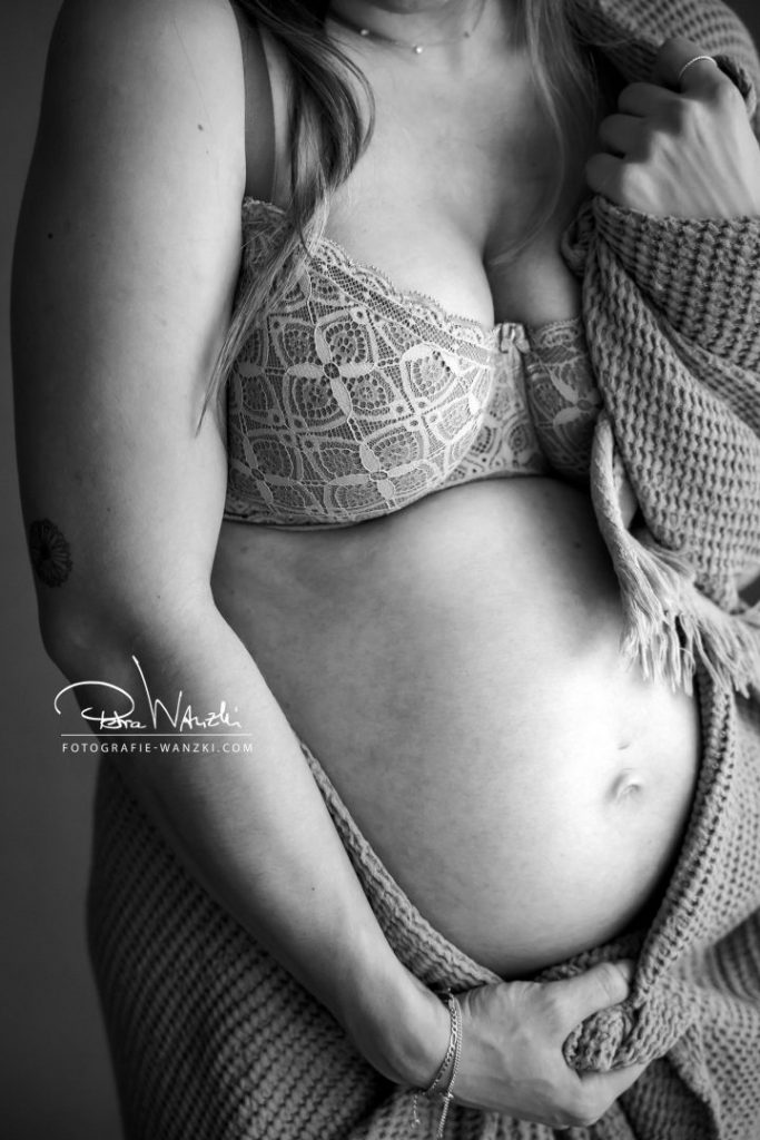 Schwangerer Bauch im Detail, Schwangere trägt Spitzenunterwäsche und ist beim FotoShooting im Fotostuio in Winterthur in eine Decke eingehüllt